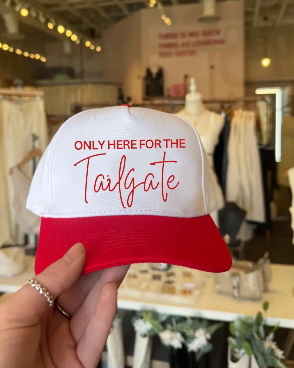 Red and white cap with text held in a store setting