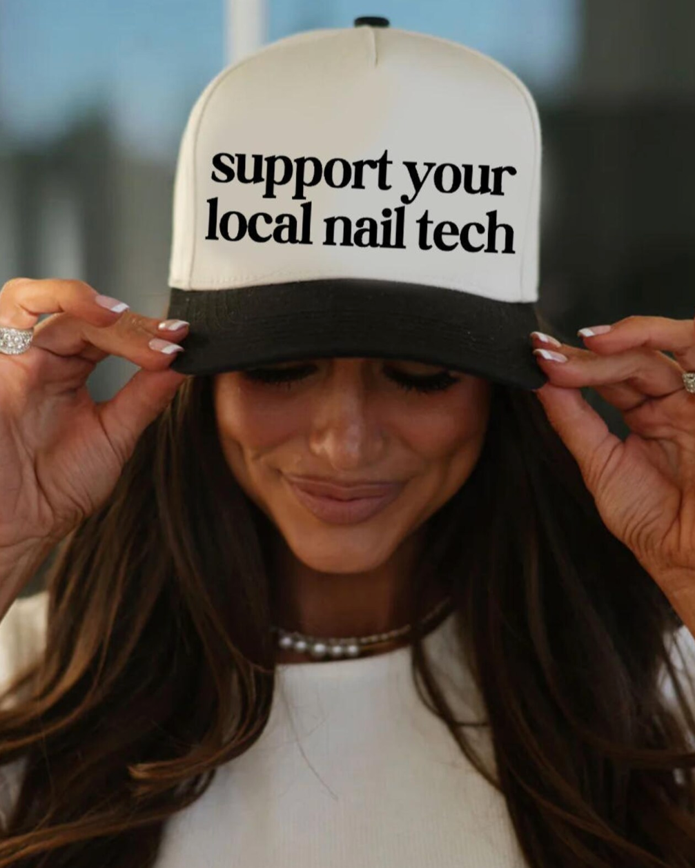 Person wearing a cap with 'support your local nail tech' text