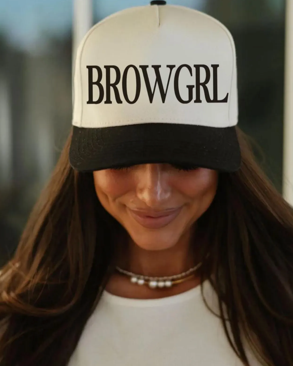Person wearing a cap with 'BROWGRL' text, blurred background