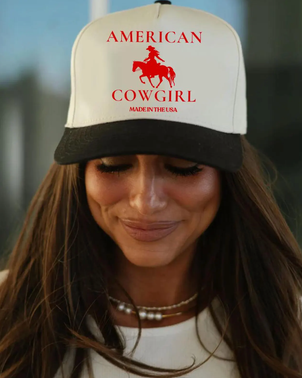 Woman wearing a 'American Cowgirl Made in USA' cap with a blurred background