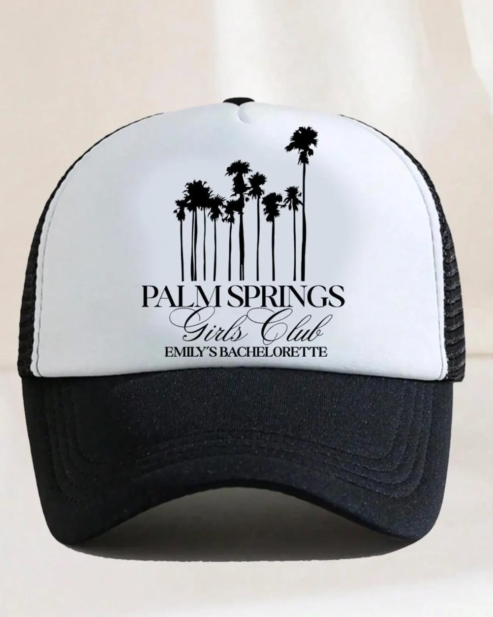 Black and white cap with palm tree design and text on a beige background