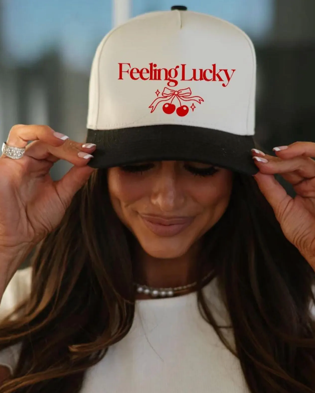 Person wearing a cap with 'Feeling Lucky' text and cherry design.