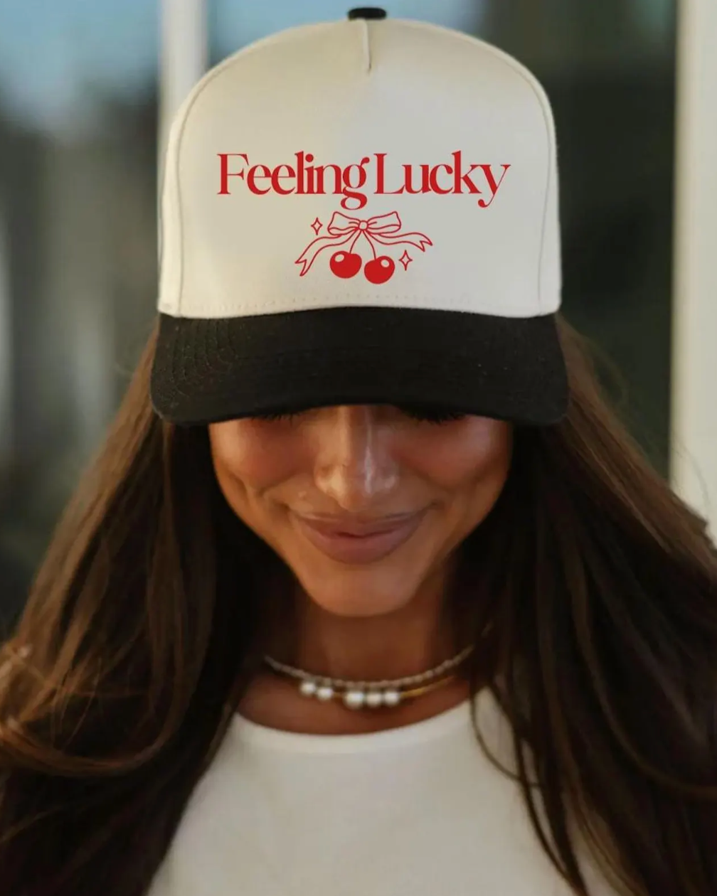 Woman wearing a cap with 'Feeling Lucky' text and cherry design.