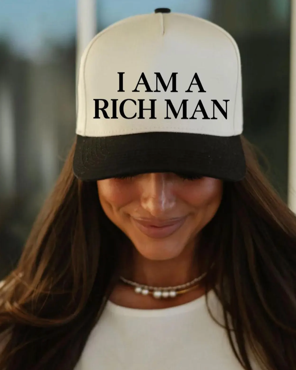 Person wearing a cap with 'I AM A RICH MAN' text