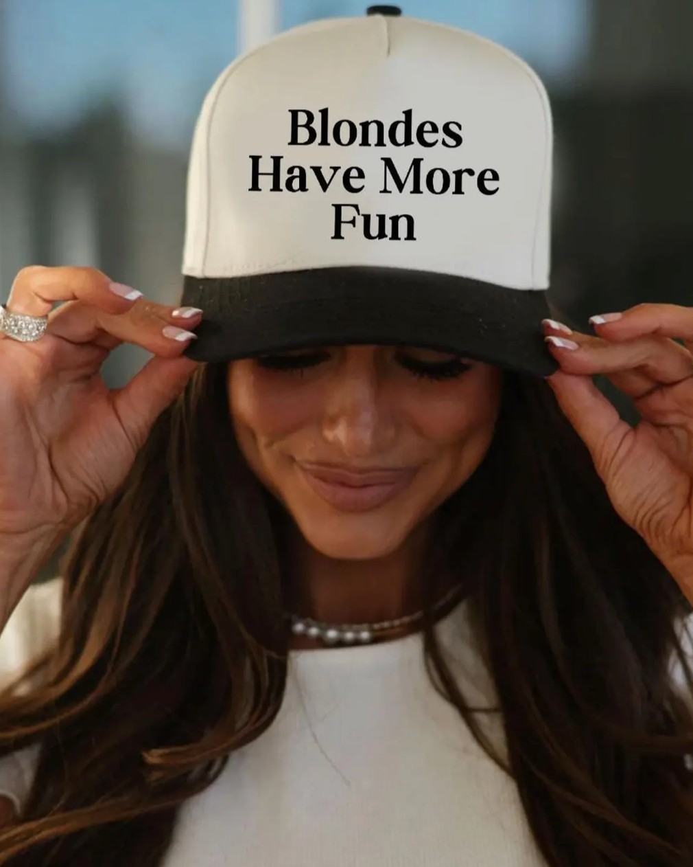 Person wearing a cap with 'Blondes Have More Fun' text