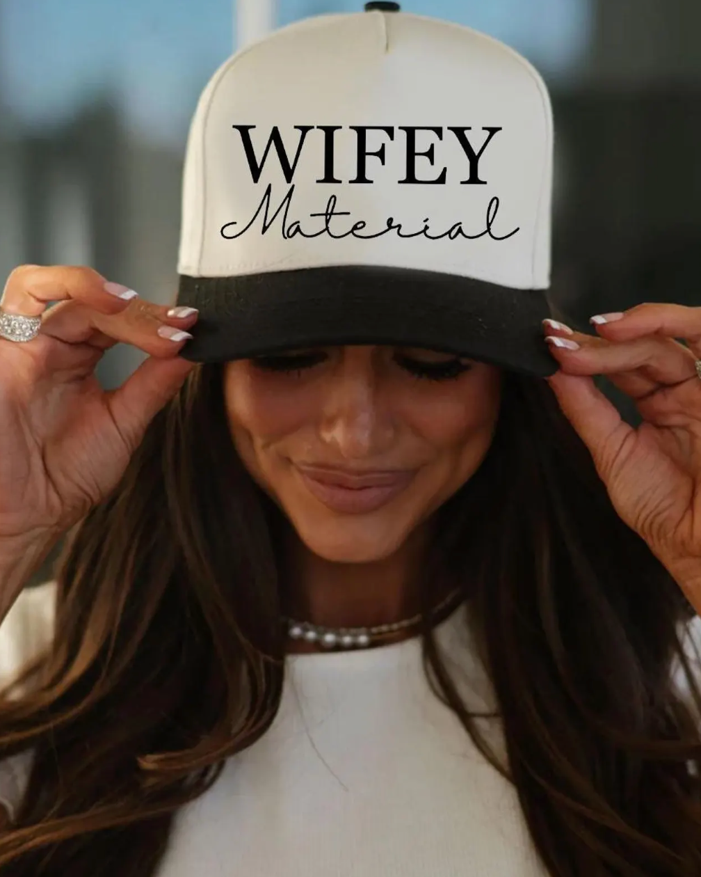 Person wearing a cap with 'WIFEY Material' text
