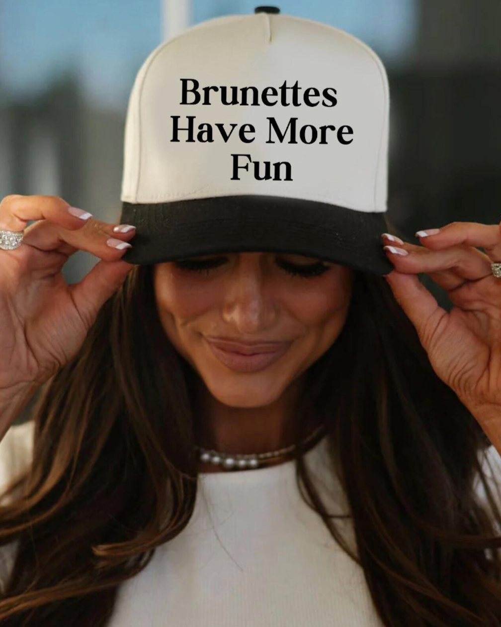 Person wearing a cap with 'Brunettes Have More Fun' text