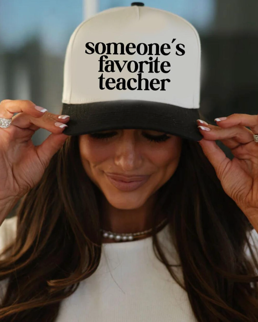 Person wearing a cap with 'someone's favorite teacher' text