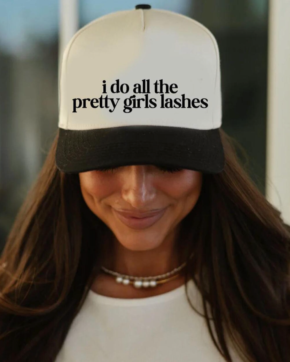 Person wearing a cap with 'i do all the pretty girls lashes' text