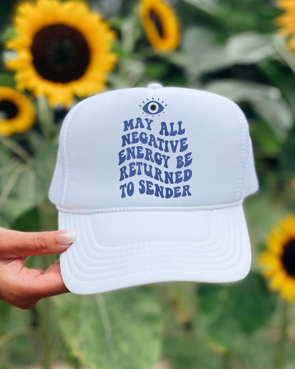 White cap with text held in front of sunflowers