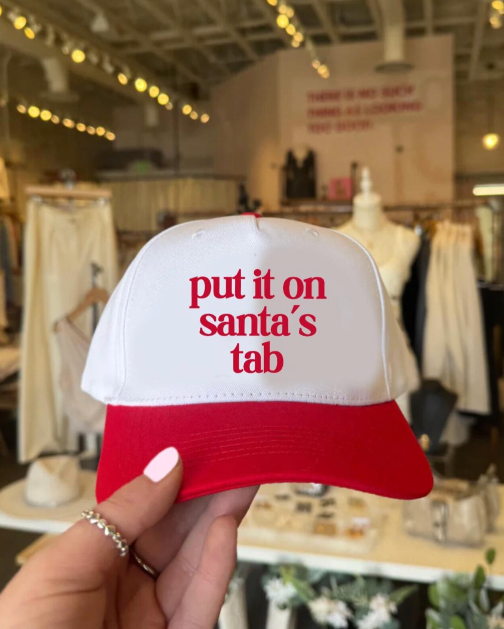 Red and white cap with text held in a store setting