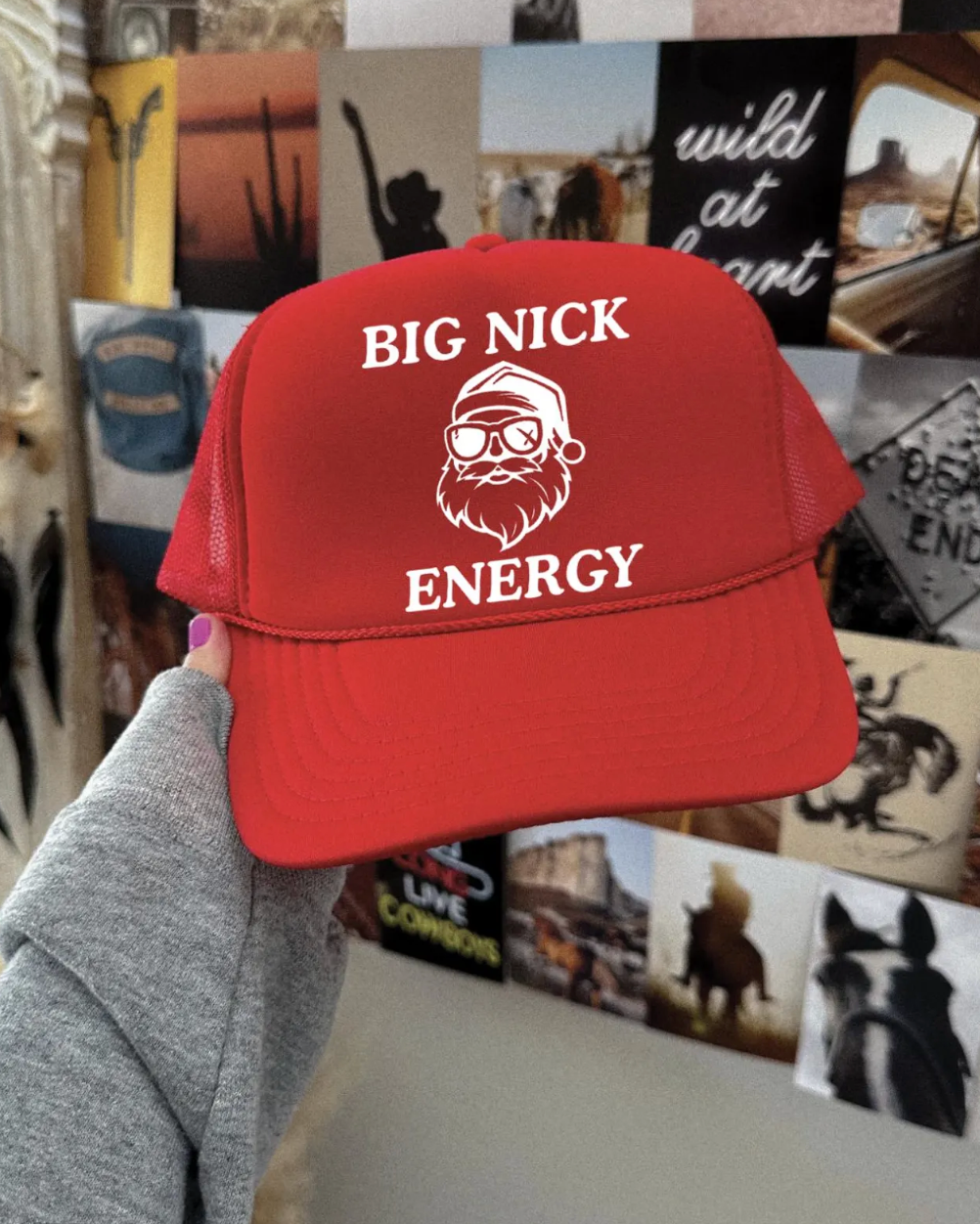 Red cap with 'BIG NICK ENERGY' text held in front of a collage of photos and posters.